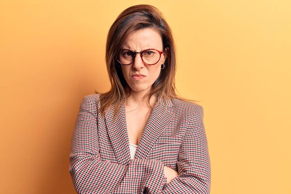 Young beautiful woman wearing business clothes and glasses skeptic and nervous, disapproving expression on face with crossed arms. negative person. 