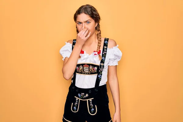 伝統的な10月祭のドレスを着て青い目を持つ若い美しいブロンドのドイツ人女性は 鼻の上に指で息を保持し 臭いと嫌な 耐え難い匂いを嗅ぐ 匂いが悪い — ストック写真