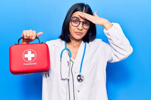 Young beautiful latin woman wearing doctor stethoscope holding first aid kit stressed and frustrated with hand on head, surprised and angry face