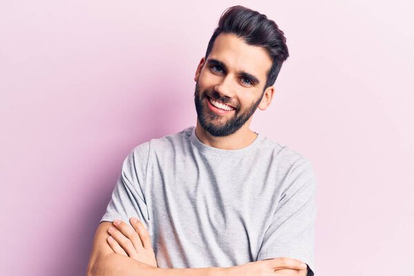 Young handsome man with beard wearing casual t-shirt happy face smiling with crossed arms looking at the camera. positive person. 