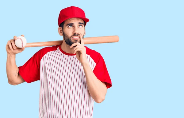 年轻英俊的男人 留着胡子 拿着棒球棒 脸上挂着严肃的表情 手托着下巴思考着问题 思考着困惑的想法 — 图库照片