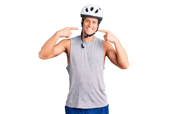 若いハンサムな男が自転車のヘルメットを着て陽気な表情と指の歯と口を指して笑顔 歯の健康の概念 — ストック写真