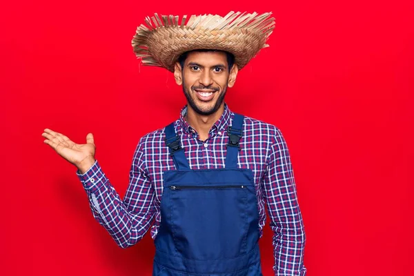 Joven Latino Con Sombrero Granjero Delantal Sonriente Alegre Presentando Señalando —  Fotos de Stock