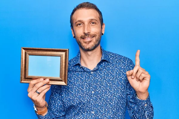 Young Handsome Man Holding Empty Frame Smiling Idea Question Pointing — Stock Photo, Image