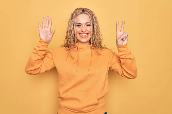 금발의 아름다운 여자가 스웨트 셔츠를 자신감 행복하게 웃으면서 손가락으로 가리키는 — 스톡 사진
