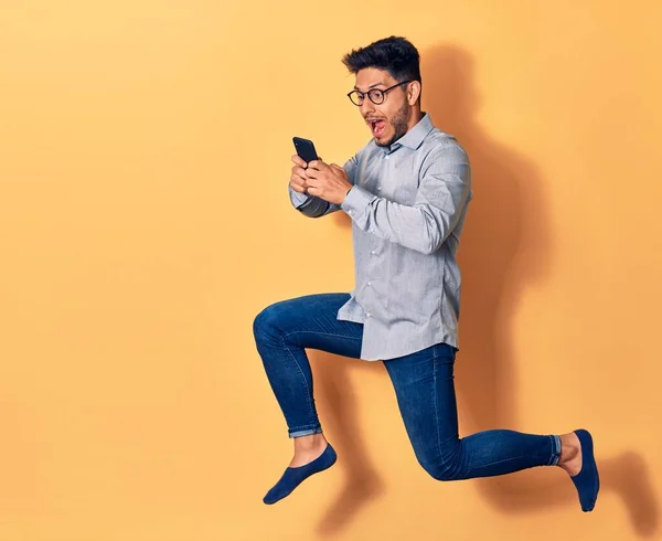 Mladý Pohledný Latinskoamerický Muž Brýlemi Poskakujícími Úsměvem Tváři Použití Smartphone — Stock fotografie