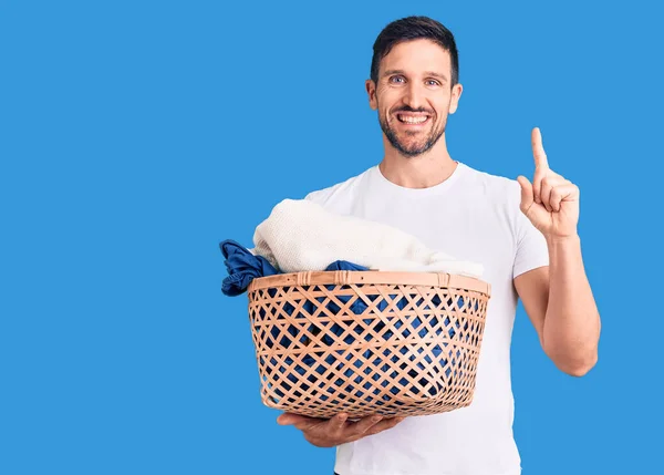 Joven Hombre Guapo Sosteniendo Cesta Ropa Sorprendida Con Una Idea — Foto de Stock