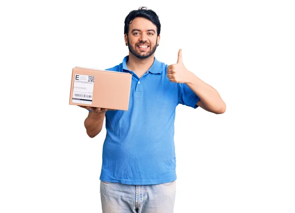 Young Hispanic Man Holding Delivery Package Smiling Happy Positive Thumb — Stock Photo, Image