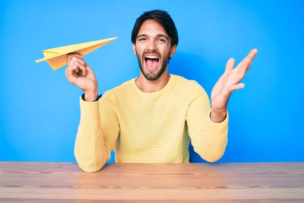 Hombre Hispano Guapo Sosteniendo Avión Papel Celebrando Victoria Con Sonrisa —  Fotos de Stock