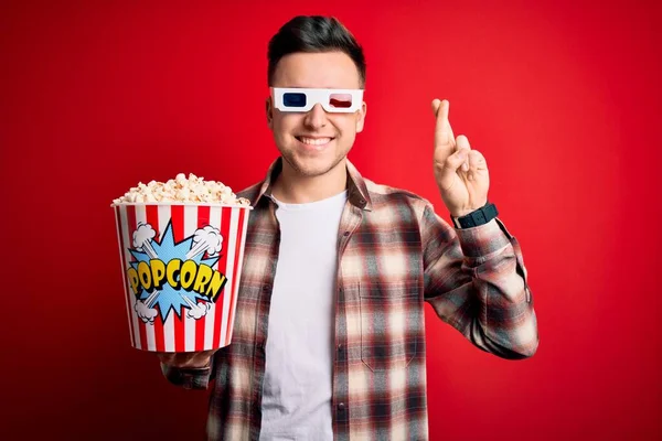 年轻英俊的高加索男子戴着3D电影眼镜 吃爆米花做手势的手指 带着希望微笑 闭上眼睛 运气和迷信观念 — 图库照片