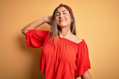 Genç, güzel, renkli bir kadın. Sarı izole edilmiş arka plan üzerinde. Yorgun ve rahat, uykulu ve sabahın erken saatleri için esniyor.