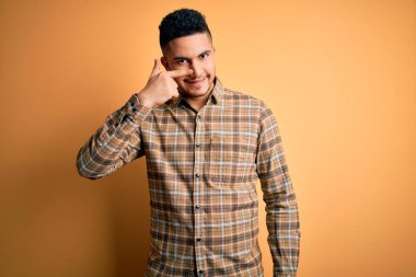 İzole edilmiş sarı arka plan üzerinde duran, el parmağı ve burunla işaret eden, neşeli gülümseyen, gündelik gömlekler giyen genç yakışıklı bir adam. Güzellik konsepti