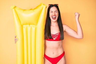 Bikini giyen beyaz bir kadın gururla bağırıyor zaferi ve başarıyı kutluyor. Kollarını kaldırarak heyecanlanıyor. 