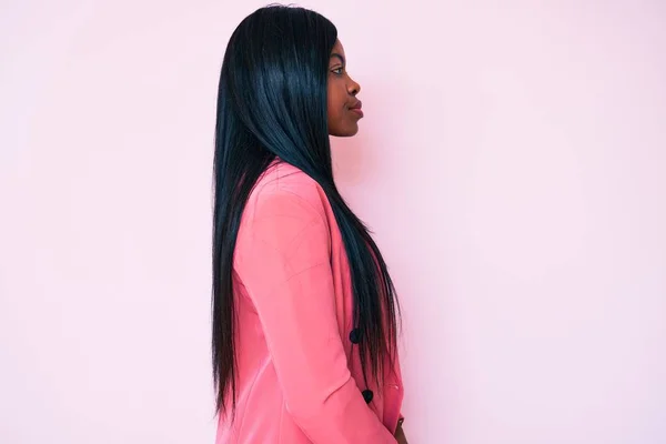 Young african american woman wearing business clothes looking to side, relax profile pose with natural face with confident smile.