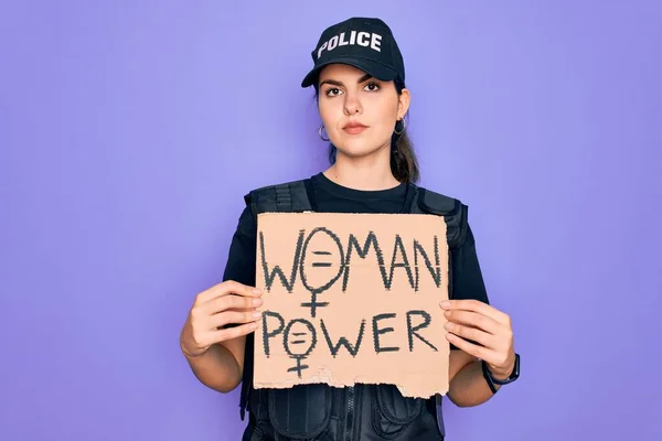 Police woman wearing security bulletproof vest uniform holding woman power protest cardboard with a confident expression on smart face thinking serious