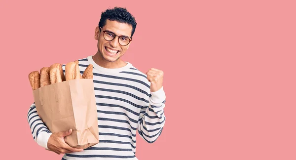 Jovem Hispânico Bonito Segurando Saco Papel Com Pão Gritando Orgulhoso — Fotografia de Stock