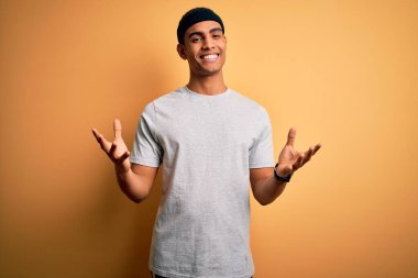 Yakışıklı Afro-Amerikan sporcusu spor giyer sarı arka plan üzerine spor giyer güler yüzlü, güler yüzlü, dostça karşılar, olumlu ve kendinden emin selamlar.