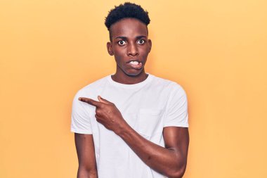 Gündelik giysiler giyen genç Afro-Amerikalı bir kenara endişeli ve endişeli bir şekilde işaret ediyor. 