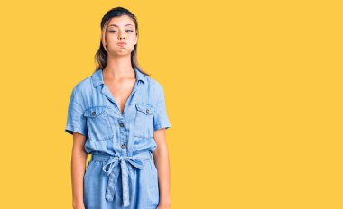 Gündelik kıyafetler giyen, komik yüzlü, yanak şişiren genç ve güzel bir kadın. Havayla şişmiş ağız, çılgın bir ifade.. 