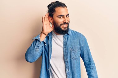 Gündelik giysiler giyen genç Arap adam, kulağı kulağında gülümsüyor, dedikodu ve dedikoduları dinliyor. Sağırlık kavramı. 