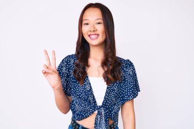 Genç, güzel, sıradan kıyafetler giyen, gülümseyen, kameraya göz kırpan, zafer işareti yapan Çinli bir kız. İki numara.. 