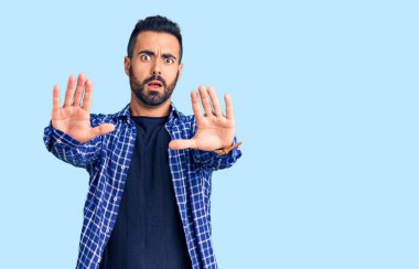 Günlük kıyafetler giyen genç İspanyol bir adam. El hareketlerini, avuç içleriyle durduruyor. Öfkeli ve hayal kırıklığına uğramış bir ifade. 