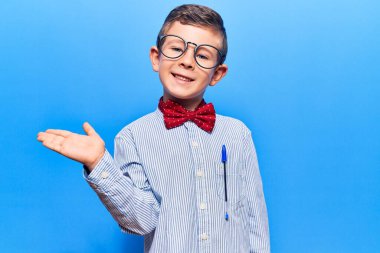 Sevimli sarışın, inek papyonlu, gözlüklü, neşeli gülümseyen, avuç içi dolu bir çocuk kameraya bakıyor.. 