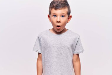 Hoş sarışın çocuk gündelik kıyafetler giyiyor. Korkmuş ve ağzı açık kalmış, şaşırmış ve şaşırmış. 