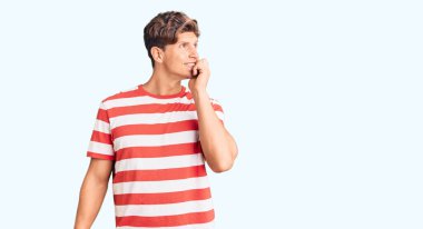 Günlük kıyafetler giyen genç yakışıklı adam gergin ve gergin görünüyor. Ağzı tırnak yiyen eller. anksiyete. 