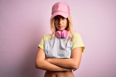 Genç ve güzel sarışın sporcu, kulaklık takarak spor yapıyor. Pembe arka planda şüpheci ve gergin. Yüzünde çapraz kollarla onaylamayan bir ifade var. Negatif kişi.