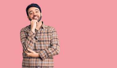 Gündelik kıyafetler giyen genç İspanyol adam kameraya kendinden emin bakıyor kollarını kavuşturup gülümsüyor ve çenesini kaldırıyor. Olumlu düşünmek. 