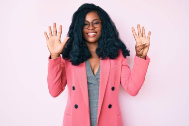 İş ceketi ve gözlük takan güzel Afrikalı kadın dokuz numarayı gösterip işaret ederken kendine güvenen ve mutlu bir şekilde gülümsüyor.. 