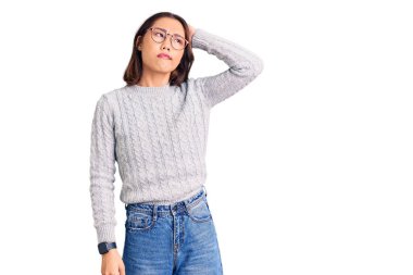 Gündelik giysiler giyen genç güzel Çinli kız kafaları karıştırıyor ve soru soruyor. Şüpheyle kararsız, kafa kafaya düşünerek. Düşünceli kavram. 