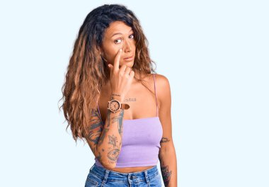 Gündelik giysiler giymiş İspanyol bir kadın. Gözünü dikip jestini izliyor. Şüpheli bir ifade. 