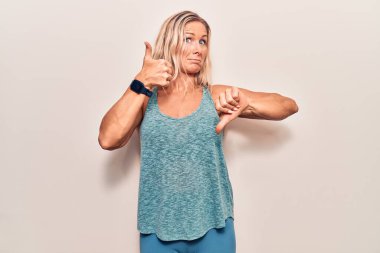 Orta yaşlı, beyaz kadın spor giyer, başparmak kaldırır, anlaşmazlık ve anlaşma ifadesi takınır. çılgın çatışma 