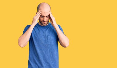 Genç ve yakışıklı bir adam stres yüzünden elleri başının üstünde rahat bir tişört giyiyor. migren ağrısı. 