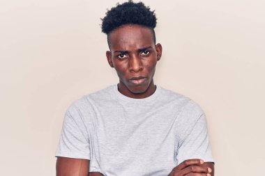 Gündelik kıyafetler giyen, kuşkucu ve gergin genç Afro-Amerikalı bir adam. Yüzünde çapraz kollarla onaylamayan bir ifade var. negatif kişi. 
