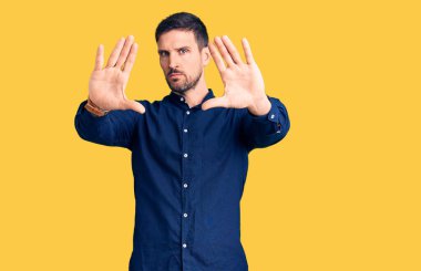 Gündelik tişört giyen, el ve parmaklarıyla çerçeve yapan genç yakışıklı bir adam. 