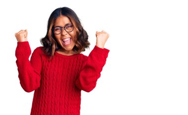 Kırmızı süveter ve gözlük takan genç ve güzel melez kadın gururla haykırıyor, zaferi ve başarıyı kutluyor kollarını kaldırarak heyecanlanıyor. 