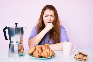 Genç kızıl saçlı kadın kahvaltı yapıyor rahatla ve gözleri kapalı gülümse parmaklarıyla meditasyon hareketi yapıyor. yoga konsepti. 