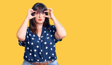 Genç ve cüsseli bir kadın günlük kıyafetler giyiyor parmaklarıyla gözlerini açmaya çalışıyor, uykulu ve yorgun bir şekilde sabah yorgunluğu çekiyor. 