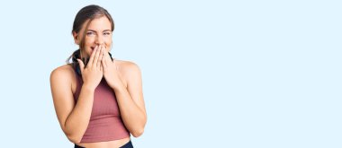 Güzel beyaz kadın spor kıyafetleri giyiyor ve kulaklık takıyor gülüyor ve utanıyor kıkırdıyor ağızları ellerle, dedikodularla ve skandallarla örtüyor. 