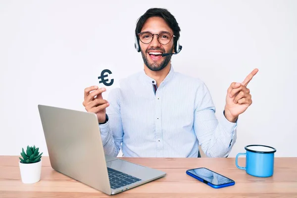 Hombre Hispano Guapo Trabajando Oficina Sosteniendo Pancarta Del Euro Sonriendo —  Fotos de Stock