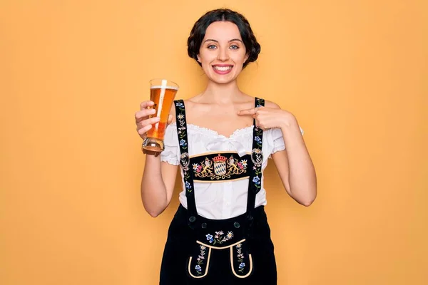 年轻美丽的德国女人 蓝眼睛 穿着十月盛装 喝着一杯啤酒 满脸惊讶地指着自己 — 图库照片
