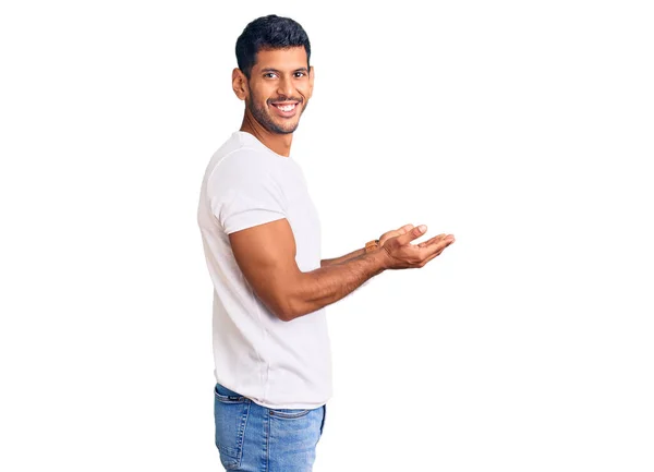 年轻的拉丁男子穿着休闲装 手拉手 手拉手地指向一边 展示复制的空间 呈现广告时面带微笑 喜形于色 — 图库照片