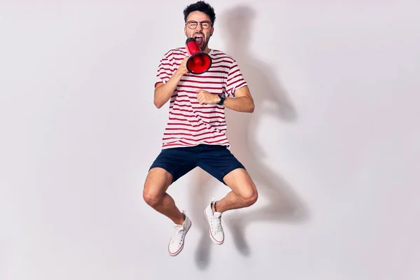 Young Handsome Hispanic Man Wearing Glasses Screaming Using Megaphone Jumping — Stock Photo, Image