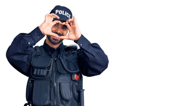 Young Hispanic Man Wearing Police Uniform Doing Heart Shape Hand Stock Picture