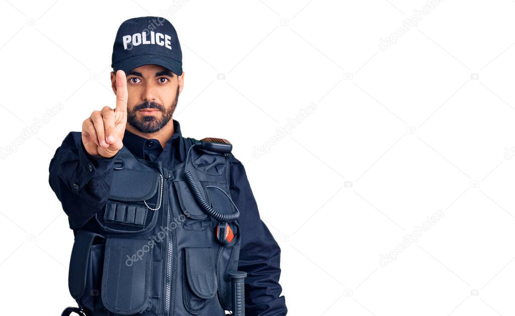 Young hispanic man wearing police uniform pointing with finger up and angry expression, showing no gesture 