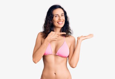 Genç ve güzel İspanyol kadın bikini giyip kameraya hayret ediyor ve gülümsüyor.. 