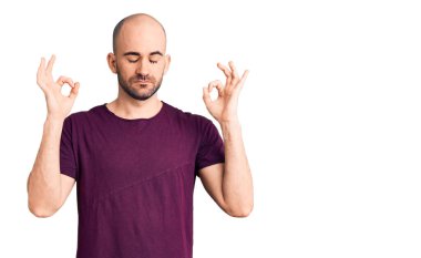 Gündelik tişört giyen genç yakışıklı adam rahatla ve gözleri kapalı gülümse parmaklarıyla meditasyon hareketi yapıyor. yoga konsepti. 